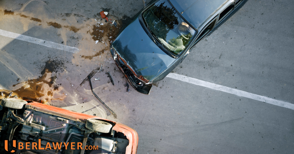 Aerial view of two cars after a collision on a road, with debris and spilled fluid across the lanes