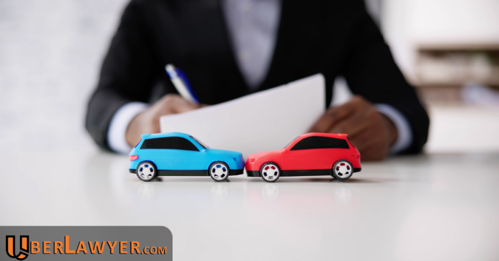 Two toy cars pushed front to front on a desk while a person fills out an insurance form behind them