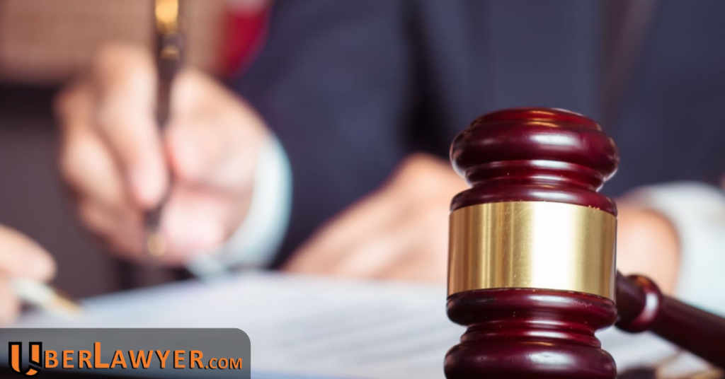 Gavel on a desk while a person signs a document in the background
